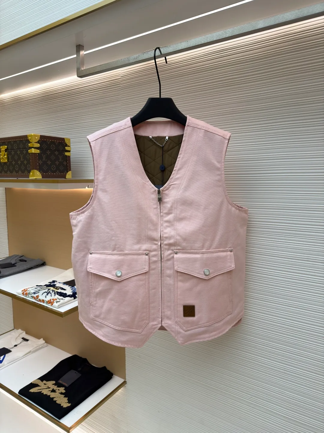 LOUIS Vuitton ●Description: This vest is made of high-quality cotton and linen blended fabrics, and the main tone of pink gives it a soft and fashionable feel. It has a V-neck design and a metal zipper placket, which is smooth and has industrial style details. The double patch pockets on the front chest have a three-dimensional structure, and the pockets are double-fastened with metal rivets and buttons to enhance practicality and decoration. A brand leather label is also embellished on the bottom of the bag to enhance recognition. The interior is quilted and the cotton batting is evenly distributed to ensure warmth and avoid clumping. The seams of the body are made of flat stitching + hemming technology, and the stitching is neat and firm, demonstrating exquisite workmanship. The overall shape is loose and moderate, combining the toughness of work clothes with the casualness of daily wear. From fabric selection to detail sewing, every craftsmanship takes into account both style expression and wearing experience. The overall wiring is straight and delicate, the fabric is comfortable and soft, and the color is consistent without color difference. It can be matched with the same style to create a fashionable look and control various occasions. Customized accessories, complete with three standards, same style for men and women!
